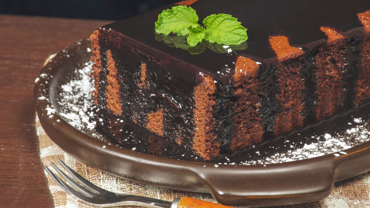 Chocolate cake homemade with chocolate topped on brown plate.