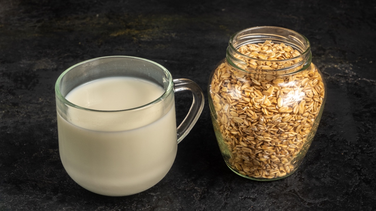 A glass of oat milk and oatmeal on a black background. Vegan milk