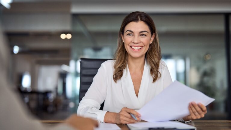 Smiling mature business woman hr holding cv (resume) document at job interview.