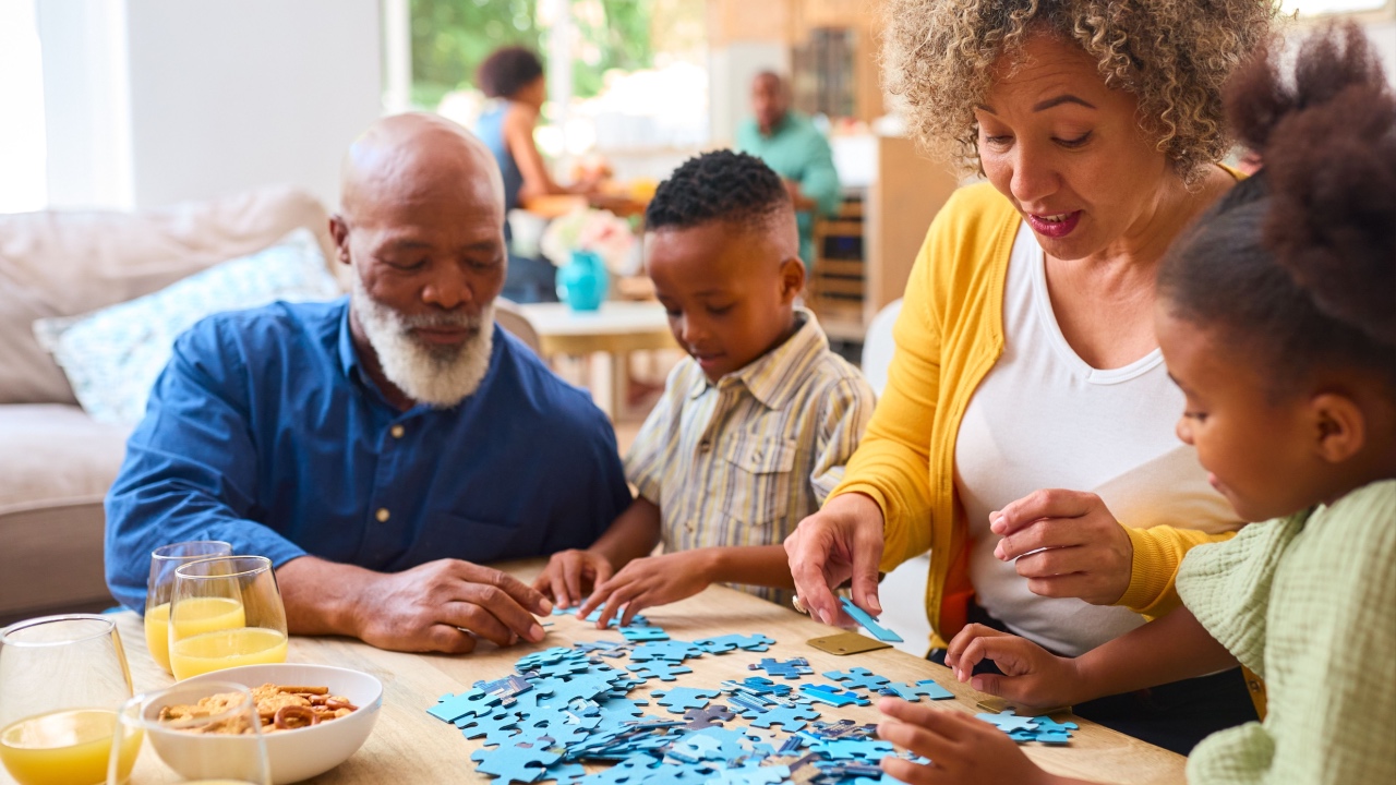 Grandparents With Grandchildren Indoors At Home Doing Jigsaw Puzzle