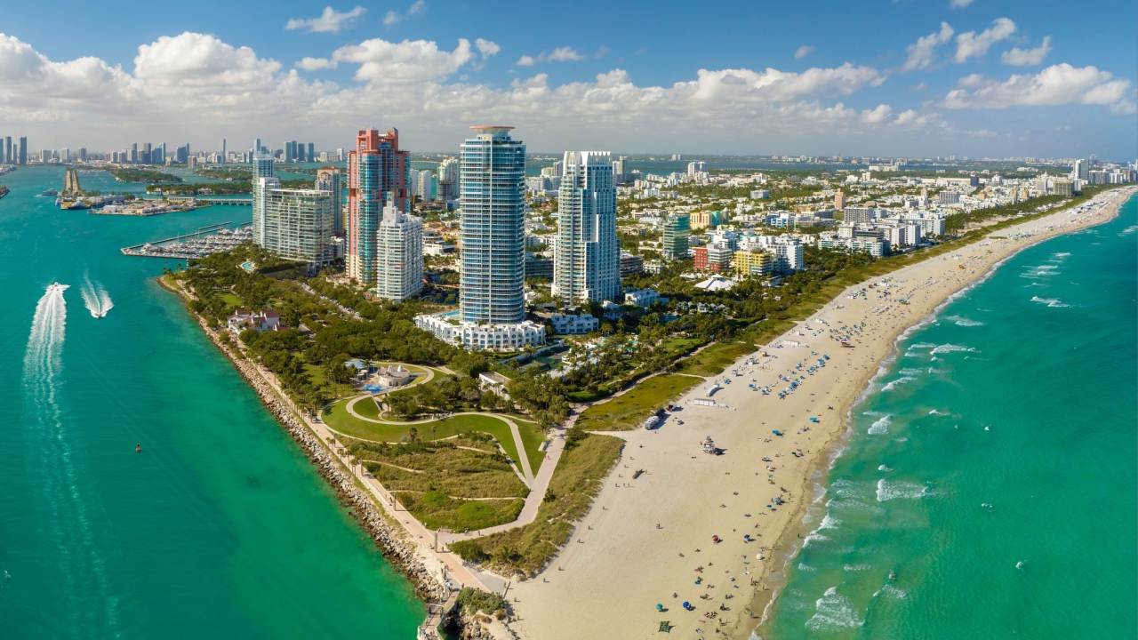 Travel destination and tourism infrastructure in southern USA. South Beach sandy surface with tourists relaxing on hot Florida sun. Miami Beach city with high luxury hotels and condos