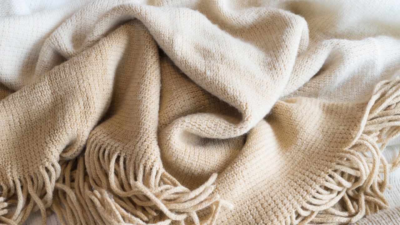 Soft neutral throw blankets with fringe in a pile. 