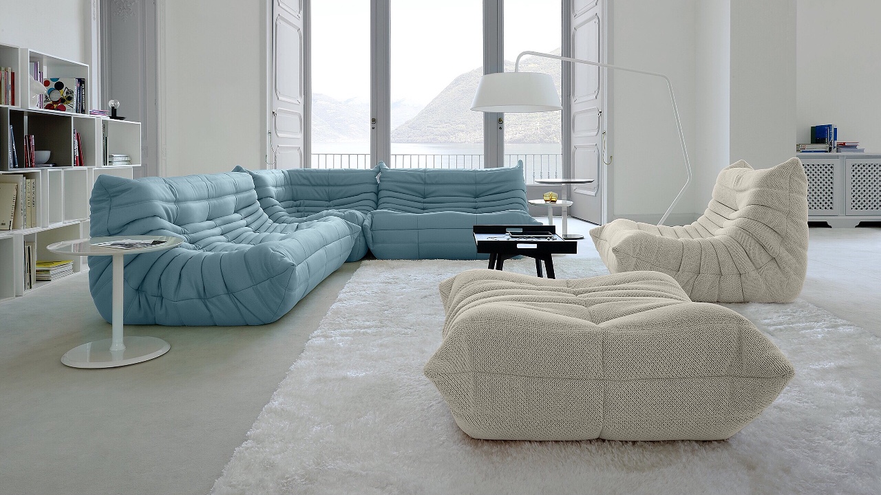 A living room with minimal decor including blue and cream colored couches.