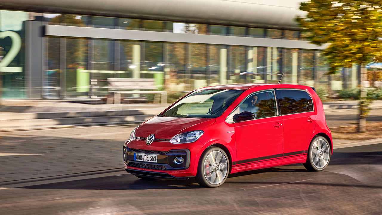 Volkswagen up! GTI, front 3/4 view, red, driving, urban area