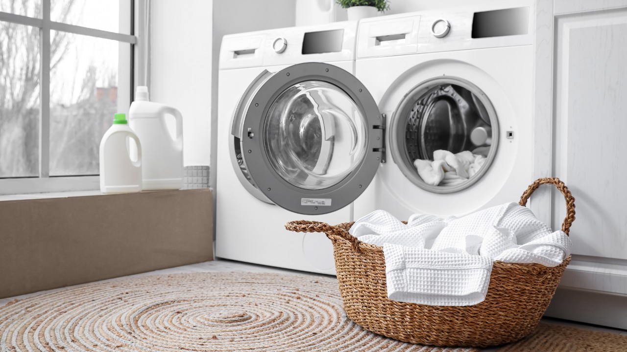 Modern washing machines with dirty clothes in laundry room.