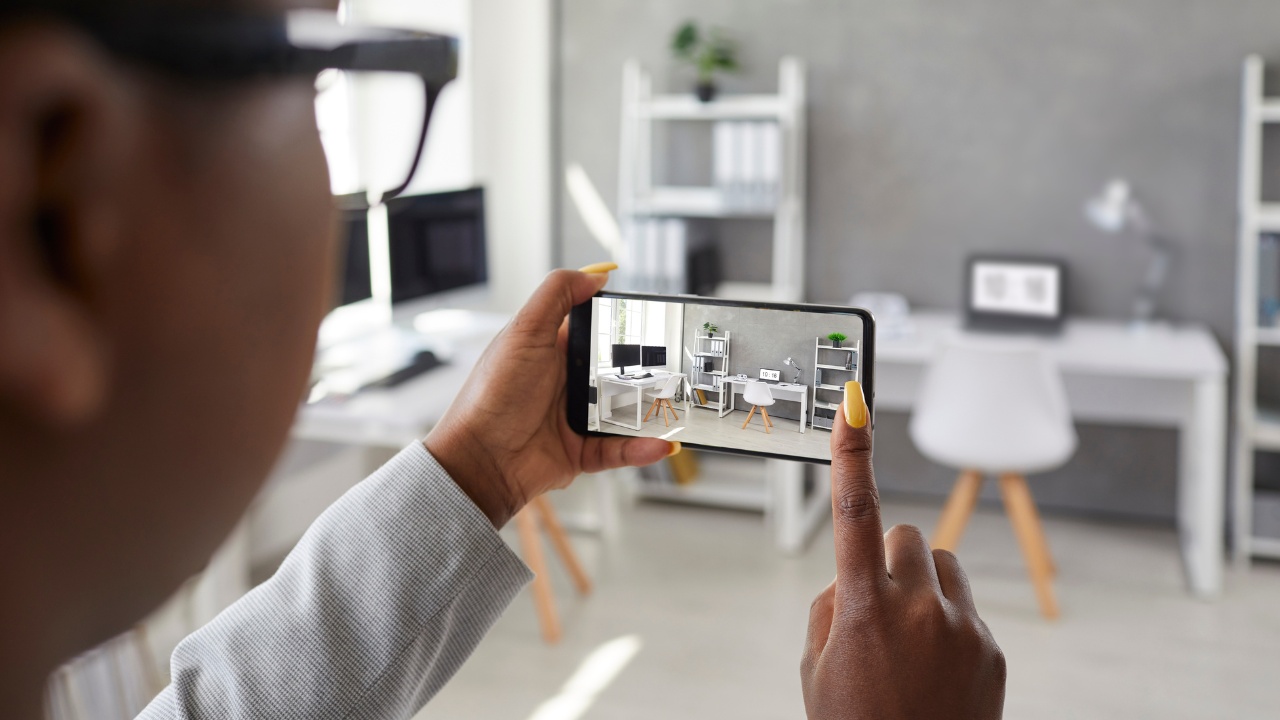 A designer taking office interior photos, making presentation or video calling client using smart phone app.