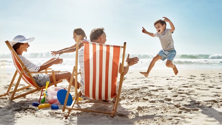 Family, children and playing at beach chair, vacation adventure and jump with bonding on summer journey. Parents, kids and excited for ocean freedom, energy and sunshine travel in Bali island