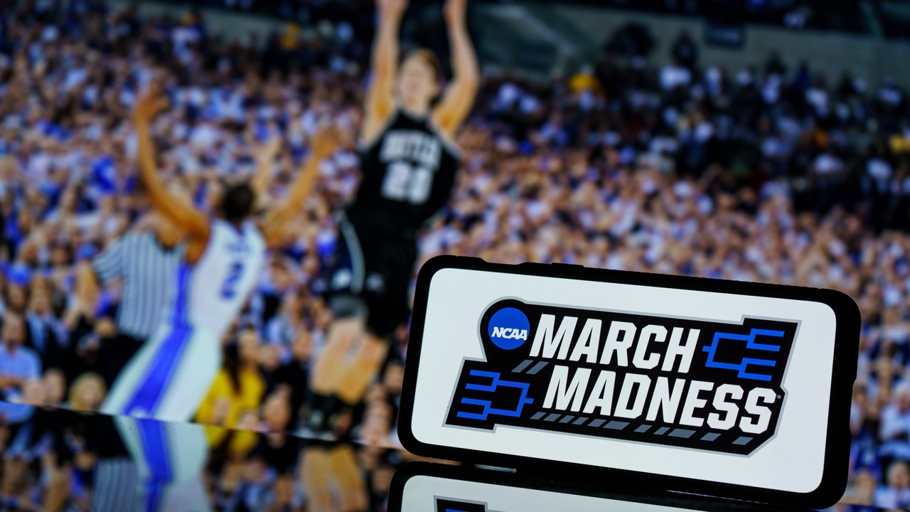 March madness logo on screen an basketball gameplay on TV screen in the background.