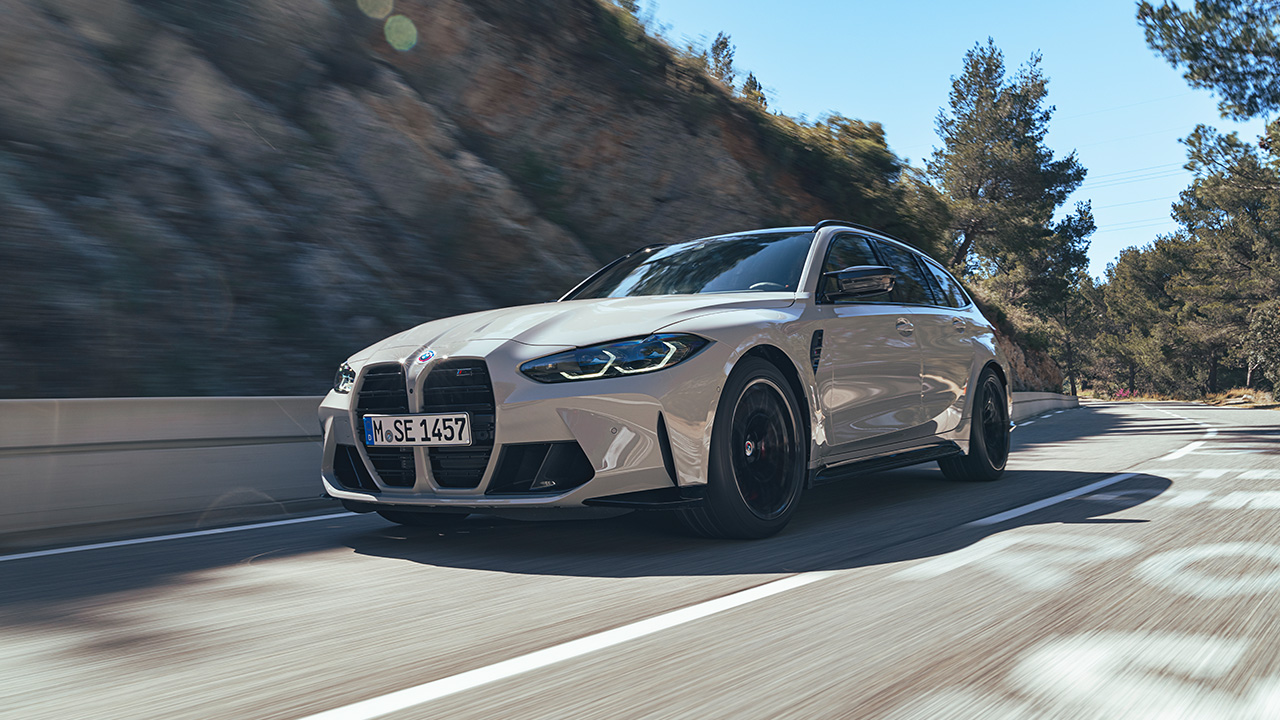 BMW M3 Touring, front 3/4 view, driving, light gray exterior