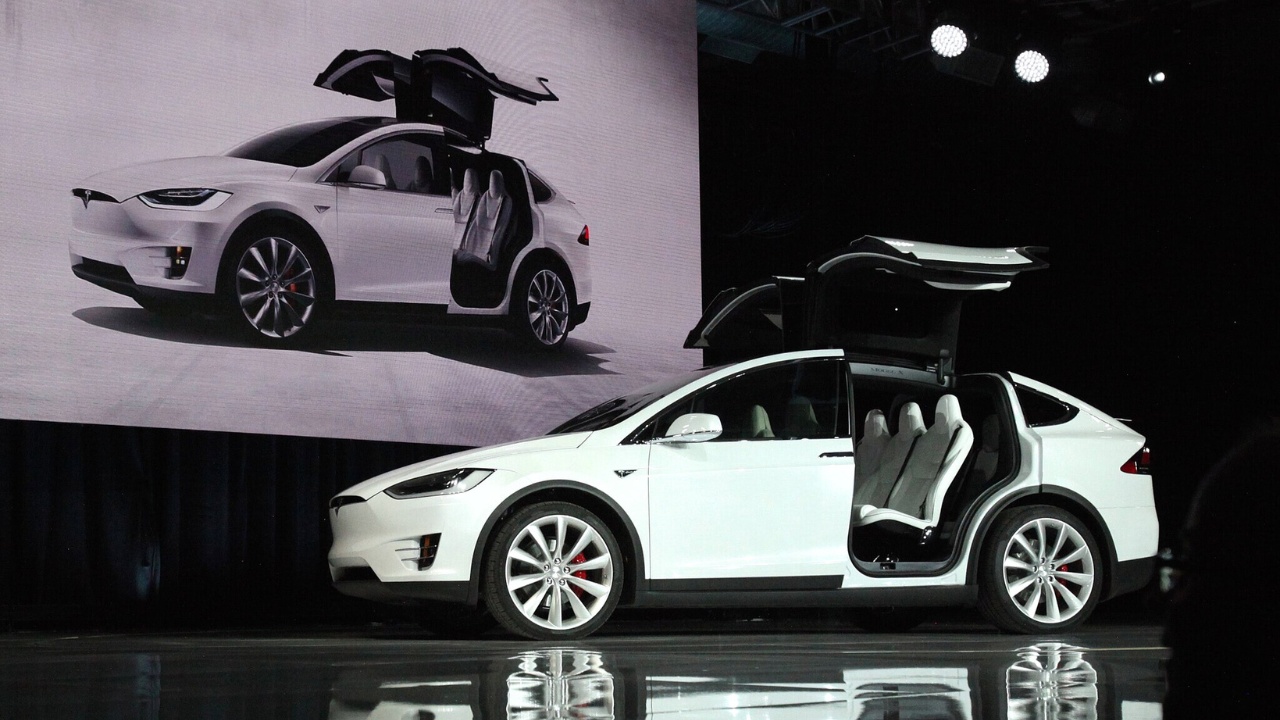 Front-side view of a white Tesla Model X at the market launch ceremony - the doors are open.