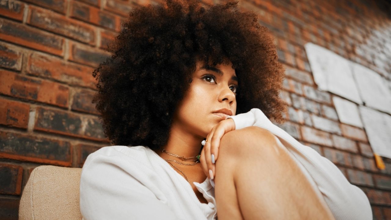 Tired, depressed and sad woman thinking of divorce, depression and anxiety stress with mental health problem on sofa in home. African girl with burnout, trauma from abuse and frustrated with mistake